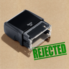 hand stamp with 'REJECTED' apple-green ink stamp on brown background