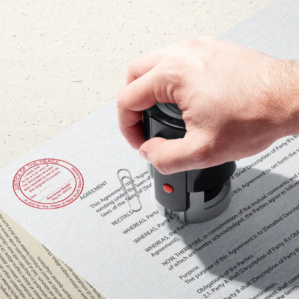 Image of Hand stamping round JP Stamp on paperwork in Red ink